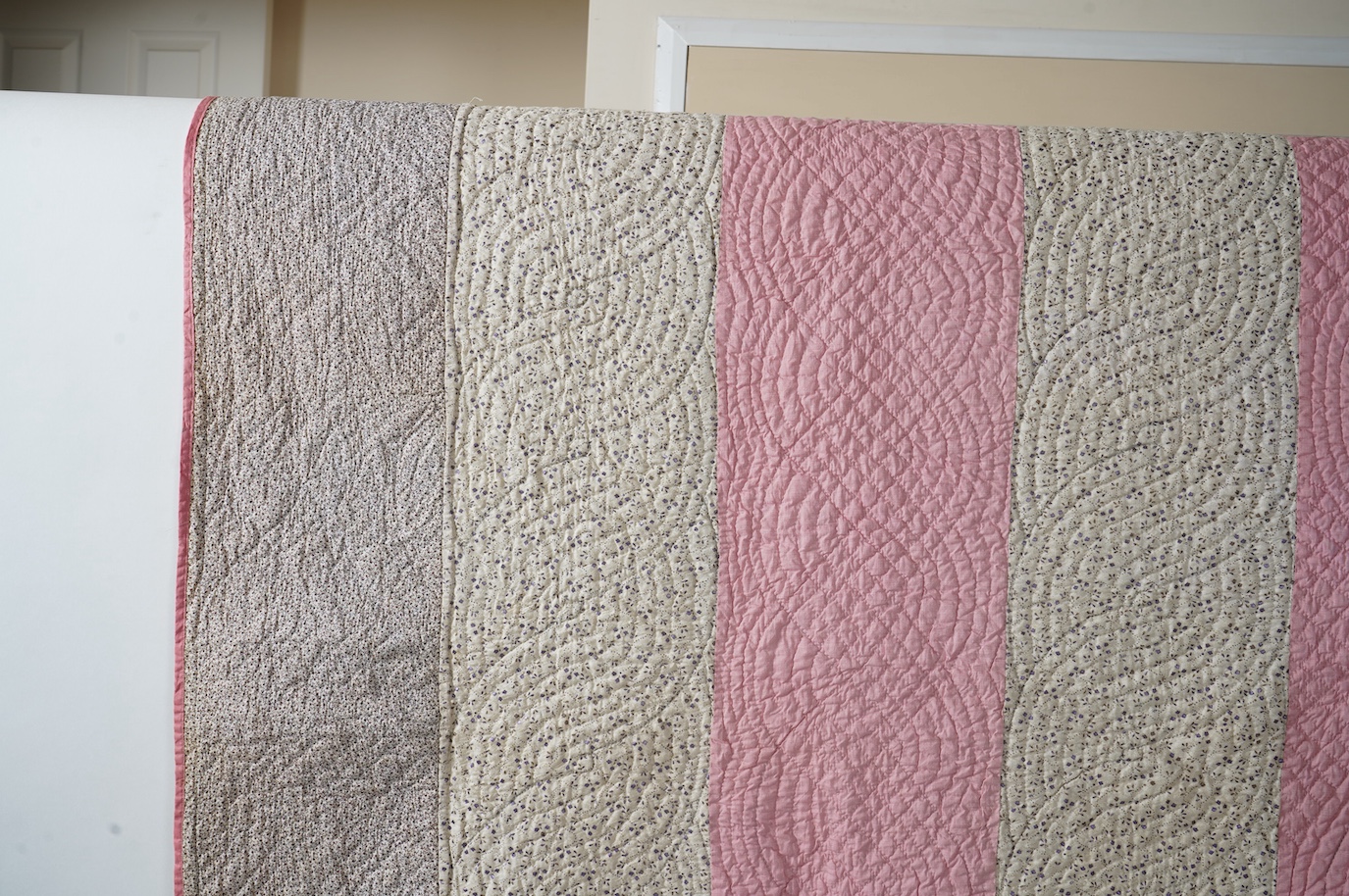 An English 19th century, highly ornate hand quilted English bedcover. Designed using alternating stripes, in a plain pink and a small printed floral cotton, then finishing with two borders of a darker minute spot floral